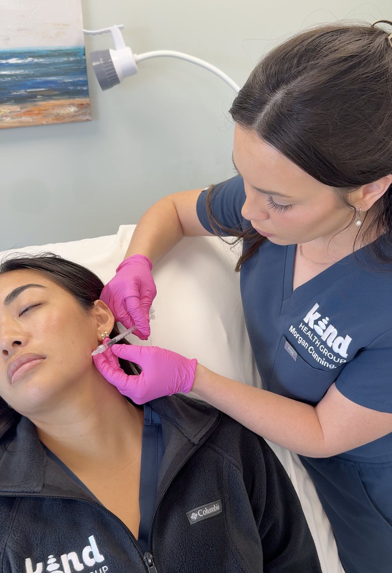 Dental clinician adjusting a patient’s ear with pink gloves during a treatment session