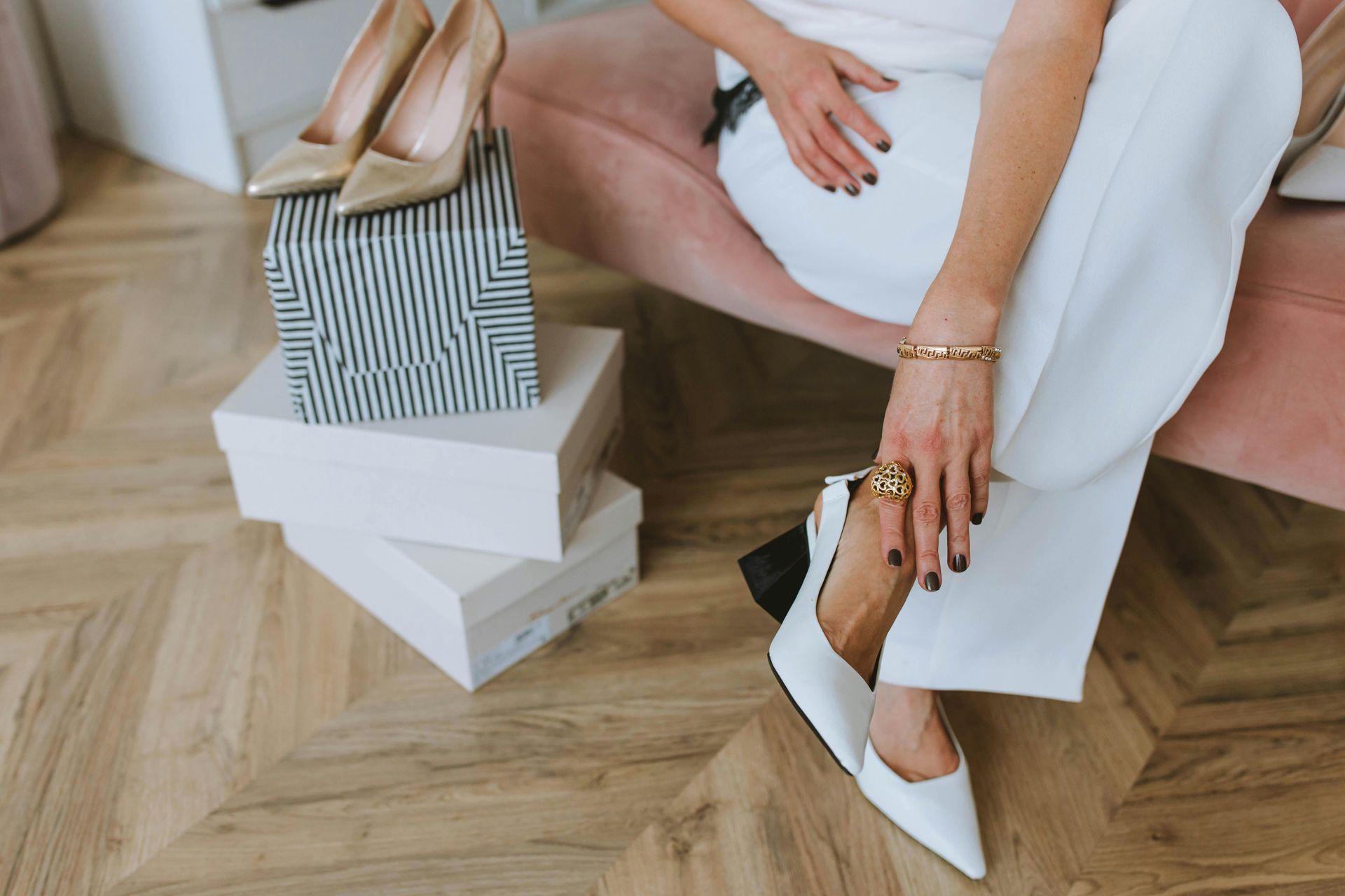 A woman is sitting on a couch next to a pile of shoes.