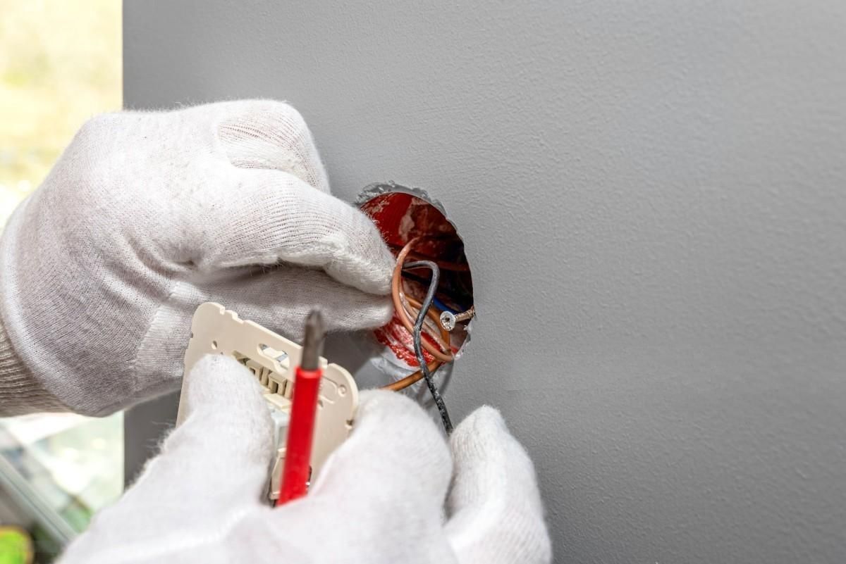 a person wearing white gloves is working on an electrical outlet