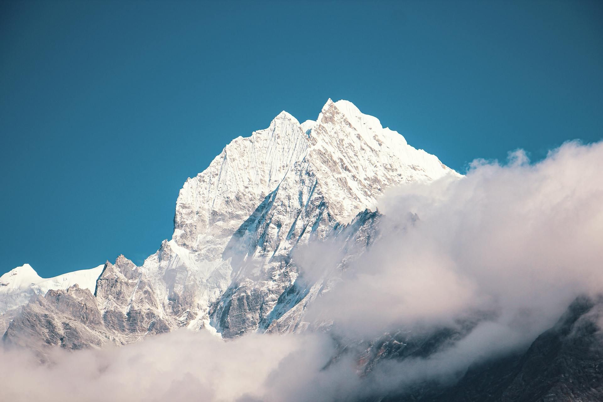 Mount Everest covered in clouds against a blue sky
