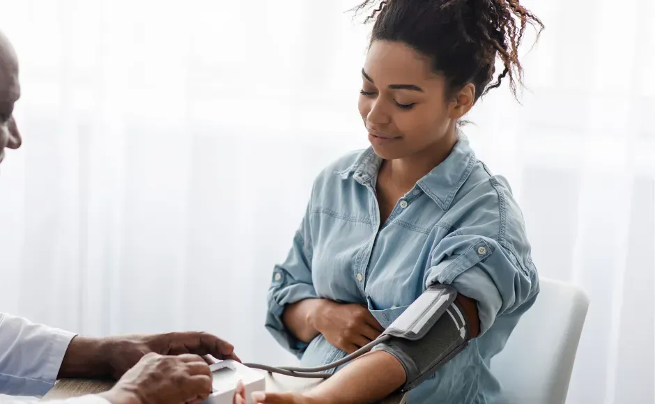 A doctor measures a patient's blood pressure with a cuff on their arm in a clinic setting.