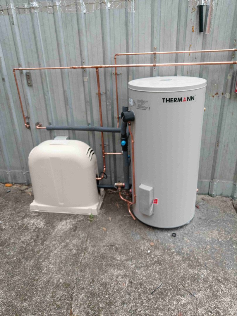 A Thermann hot water system and pump in an outdoor setting with copper pipes.