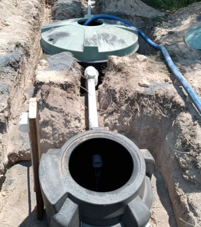 A Septic Tank is Sitting in the Dirt Next to a Hose — Greg Mitchell Plumbing In Murgon, QLD