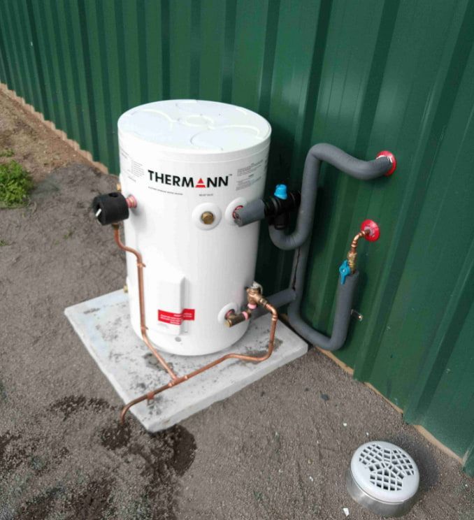 A White Thermo Nin Water Heater is Sitting Next to a Green Wall — Greg Mitchell Plumbing In Murgon, QLD