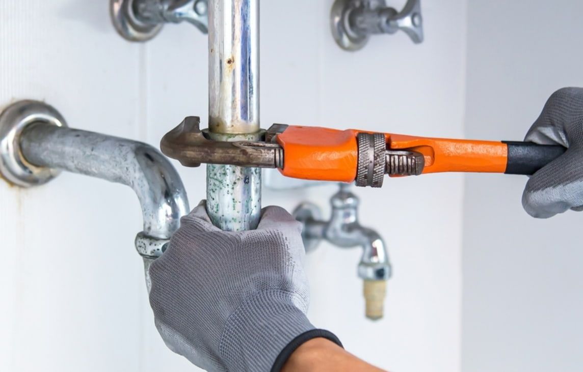A Plumber is Fixing a Pipe With a Wrench — Greg Mitchell Plumbing In Murgon, QLD