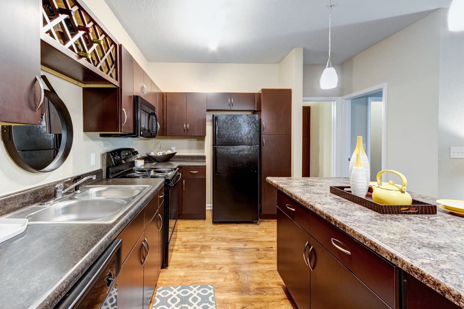 Dark brown kitchen with black appliances and an island at The Preserve at Essex Farms, offers apartments in Charleston, SC.