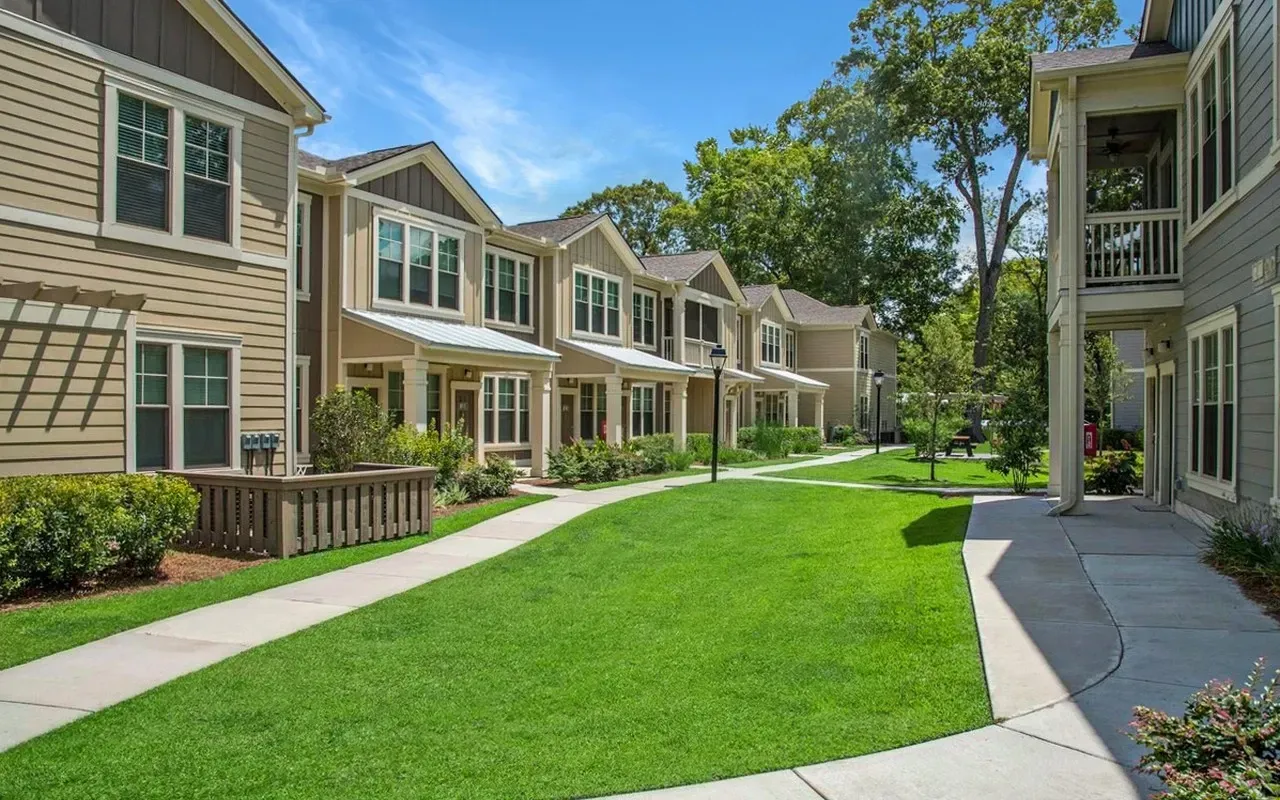 A row of houses with a lush green lawn in front of them at The Preserve at Essex Farms, offers apartments in West Charleston, SC.