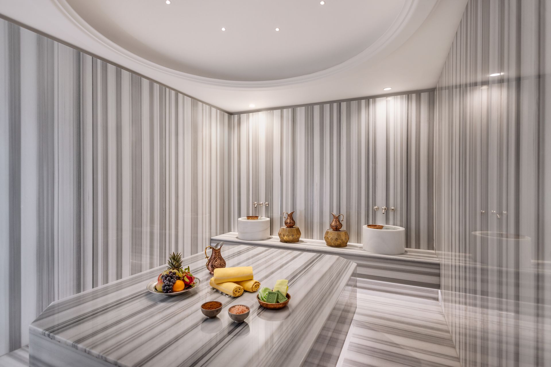 There is a table with fruit on it in the middle of the room.