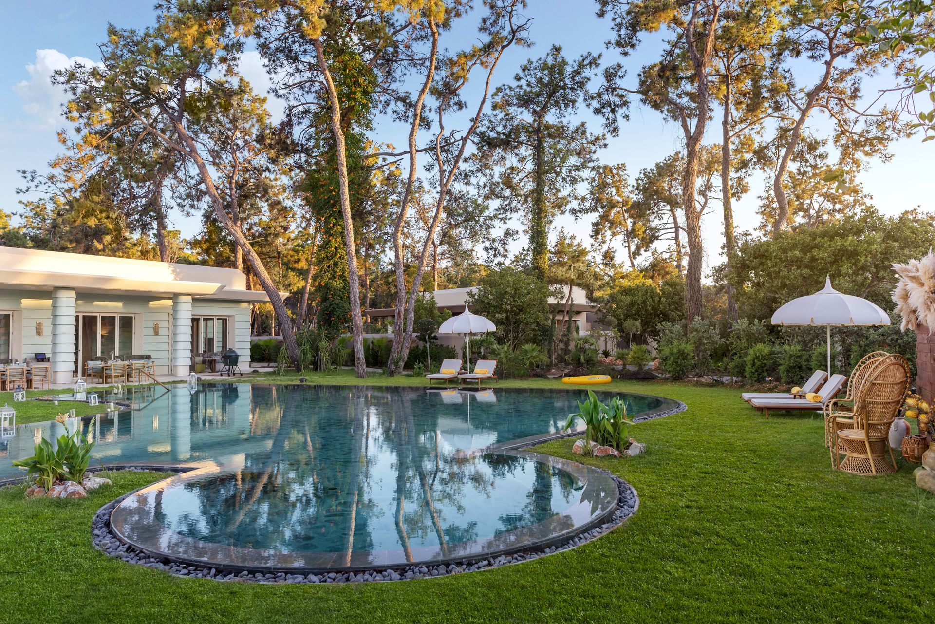 A large swimming pool in the middle of a lush green yard surrounded by trees.