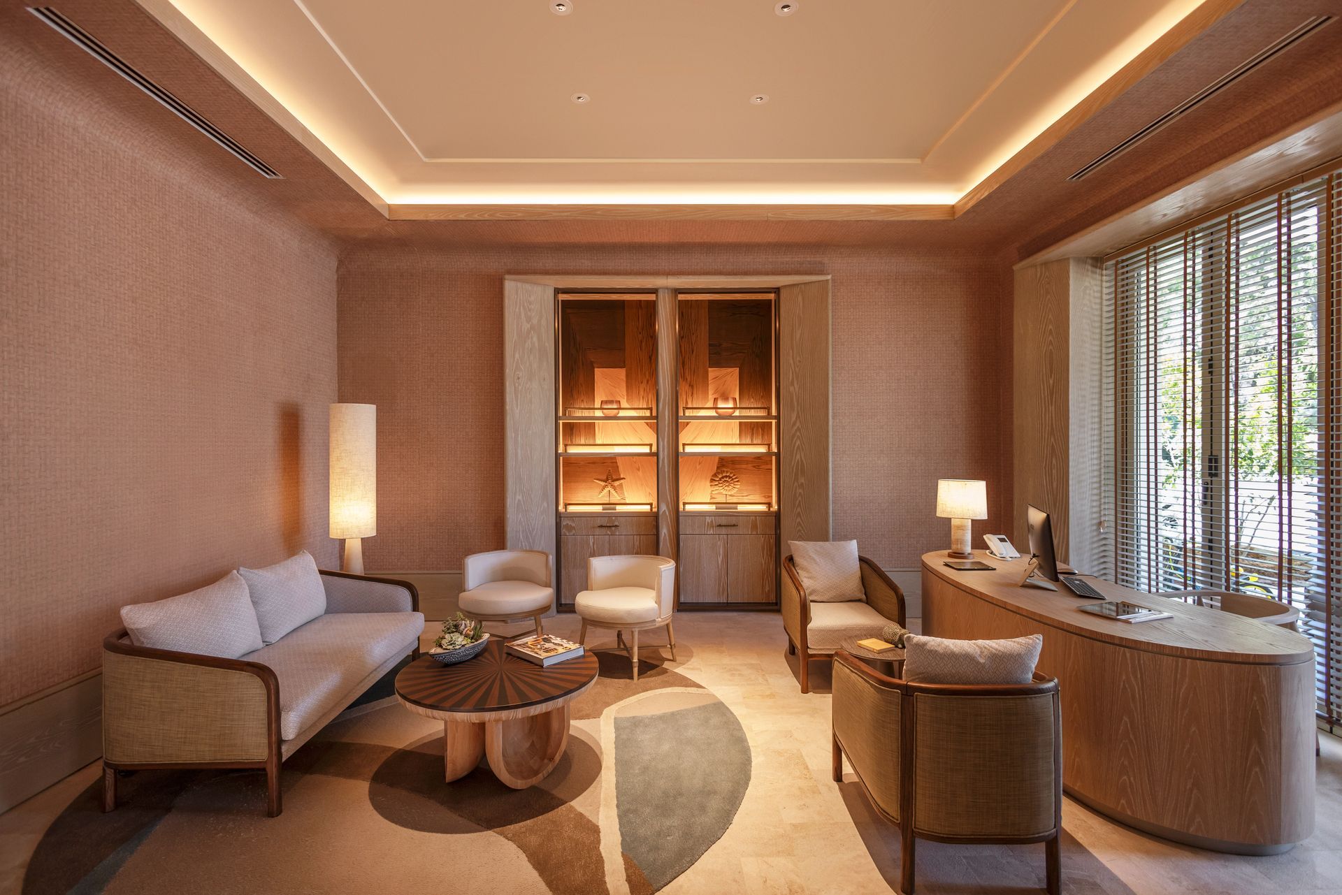 A living room with a couch , chairs , a table and a desk.