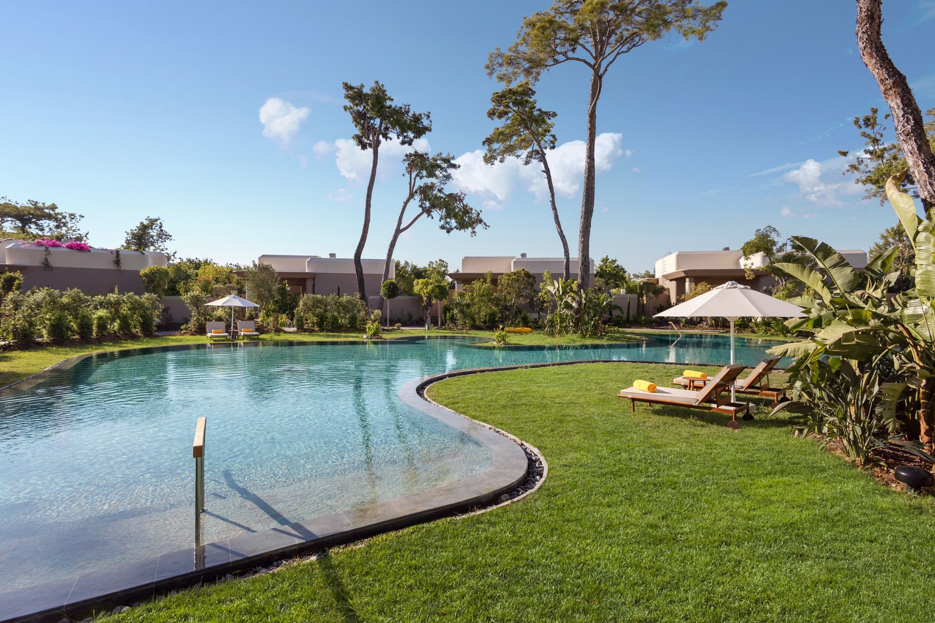 A large swimming pool surrounded by lawn chairs and umbrellas