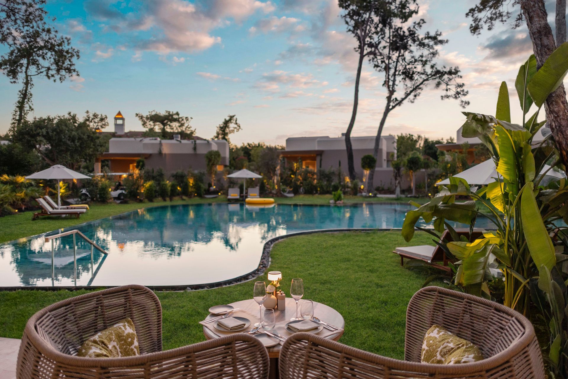 Two chairs are sitting at a table in front of a large swimming pool.