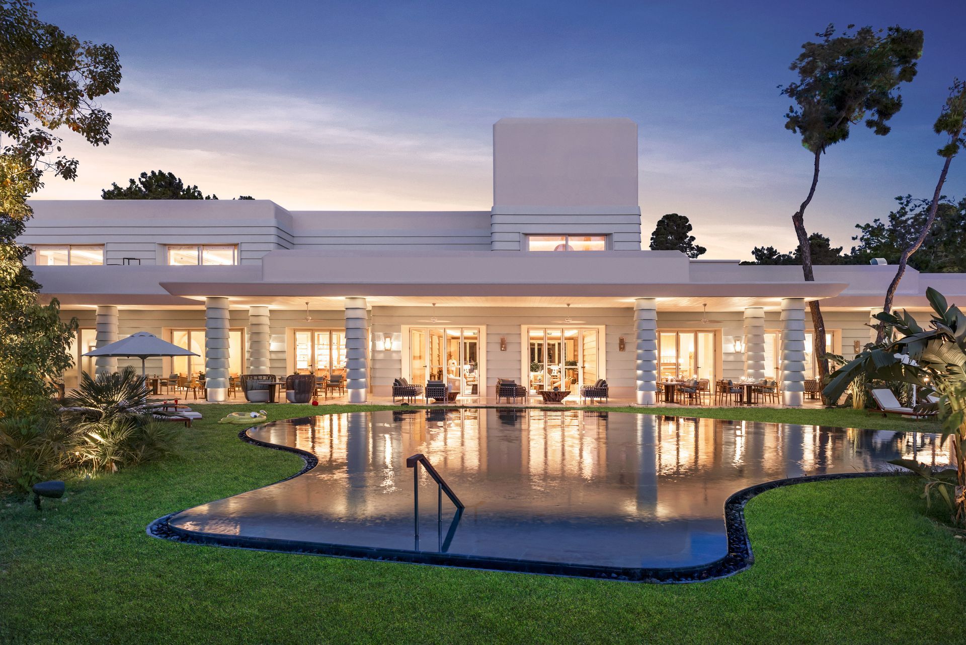 A large white house with a large swimming pool in front of it.