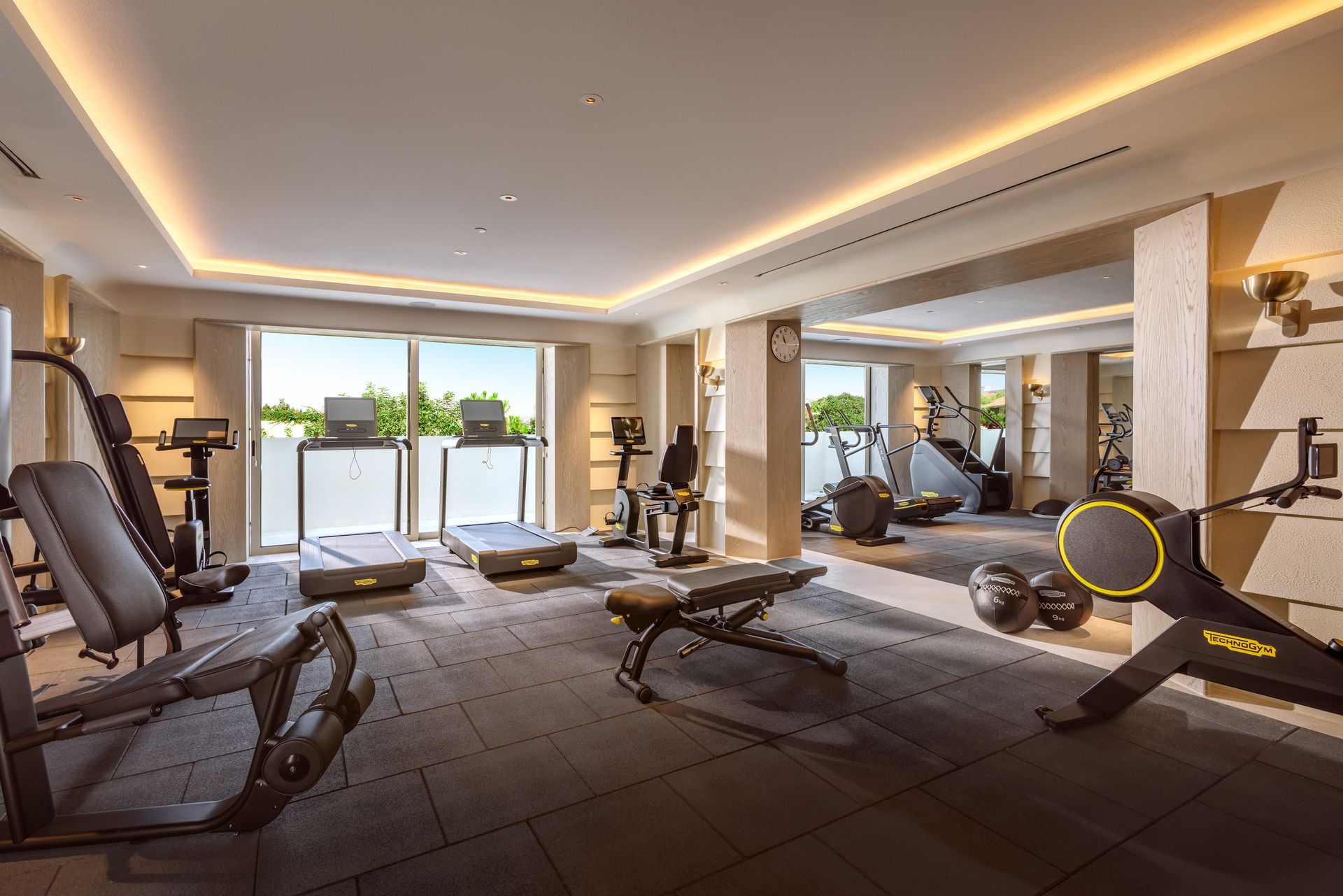 A large gym with a lot of equipment and a large mirror.