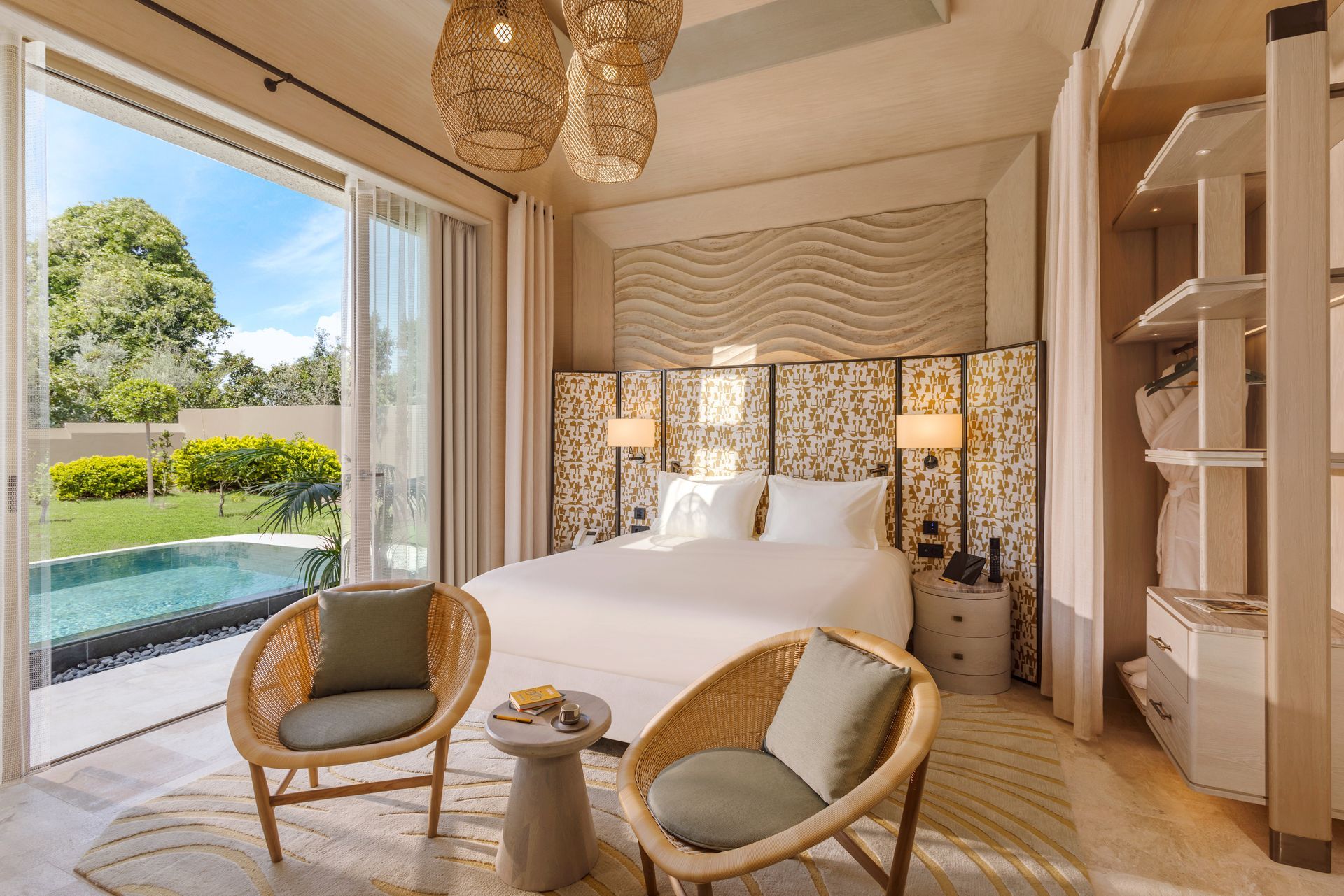 A bedroom with a king size bed , two chairs , a table and a sliding glass door.