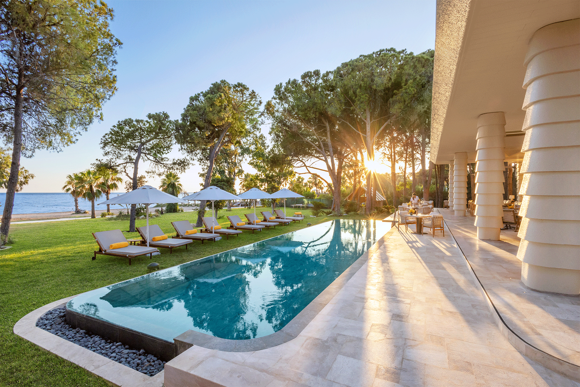 A large swimming pool surrounded by lawn chairs and umbrellas