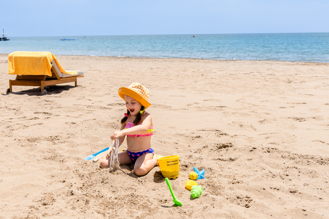 A little girl is playing in the sand on the beach.