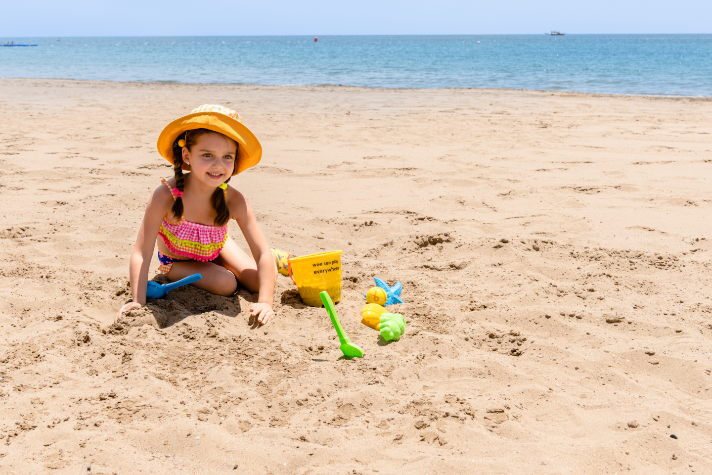 A little girl is playing in the sand on the beach.