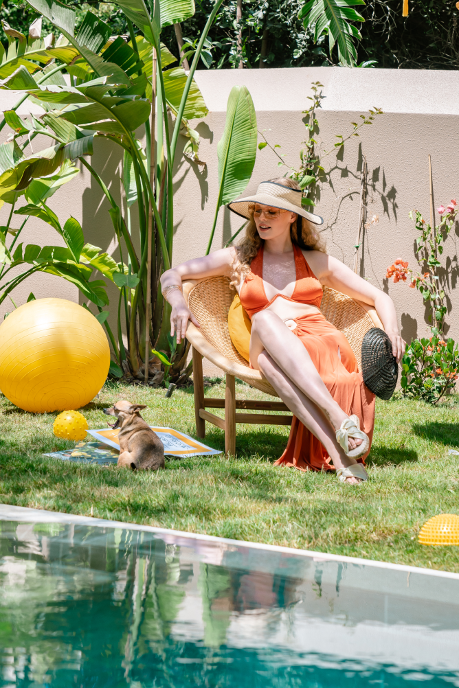 A woman is sitting in a chair next to a swimming pool.
