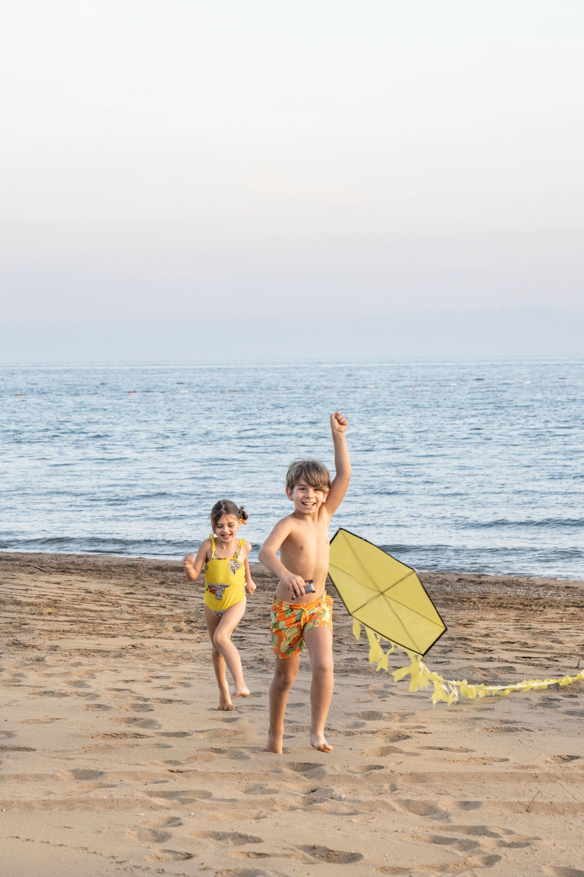 A boy and a girl are flying a kite on the beach.