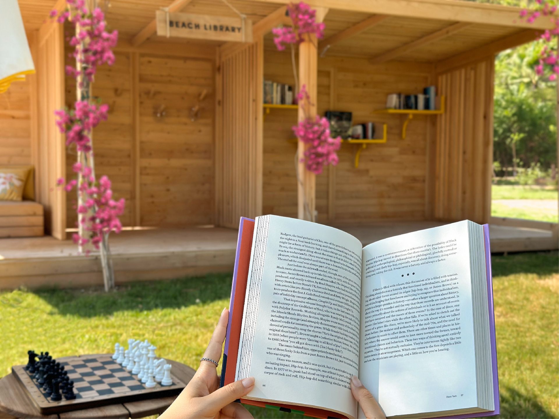 A person is holding an open book in front of a wooden library