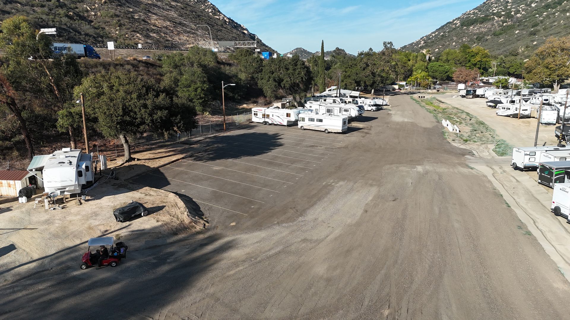Inflatable boat on trailer, covered by a tarp, parked under a carport.
