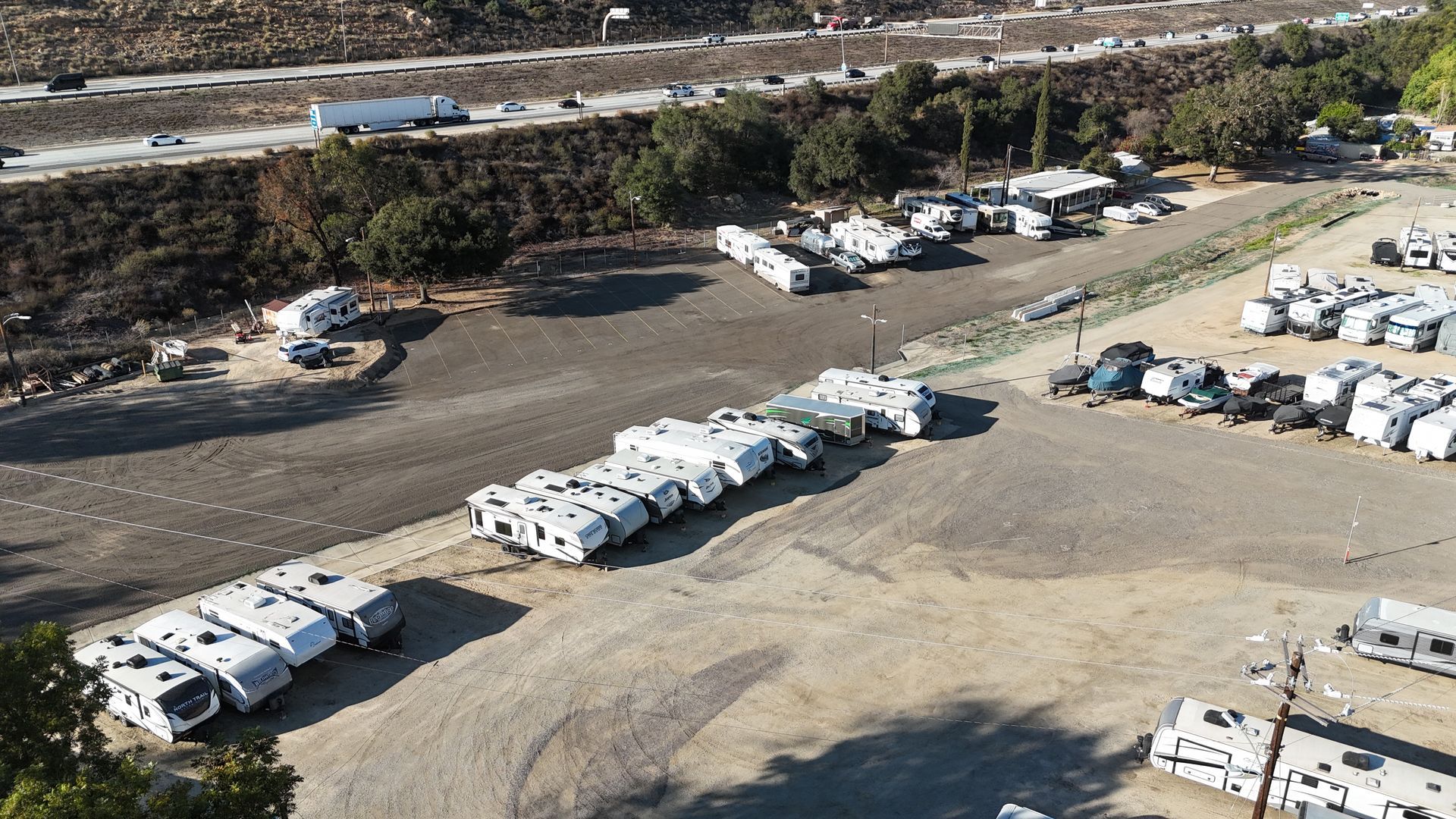 Boat on trailer inside a large garage-like space with a closed door, open garage door, and equipment overhead.