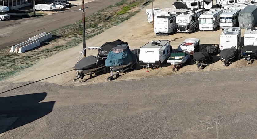 Sailboats on stands in a shipyard, against a bright blue sky.