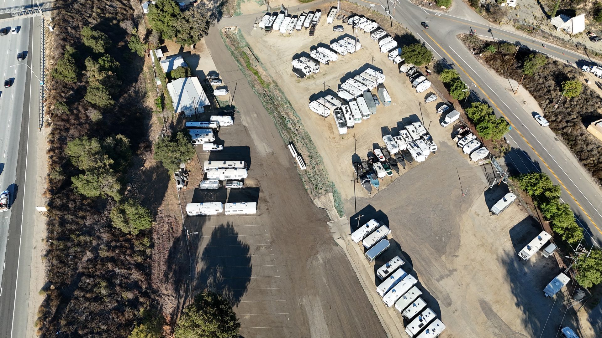 Empty parking lot with white lines, stone wall with overhang, and a building with red tile roof.
