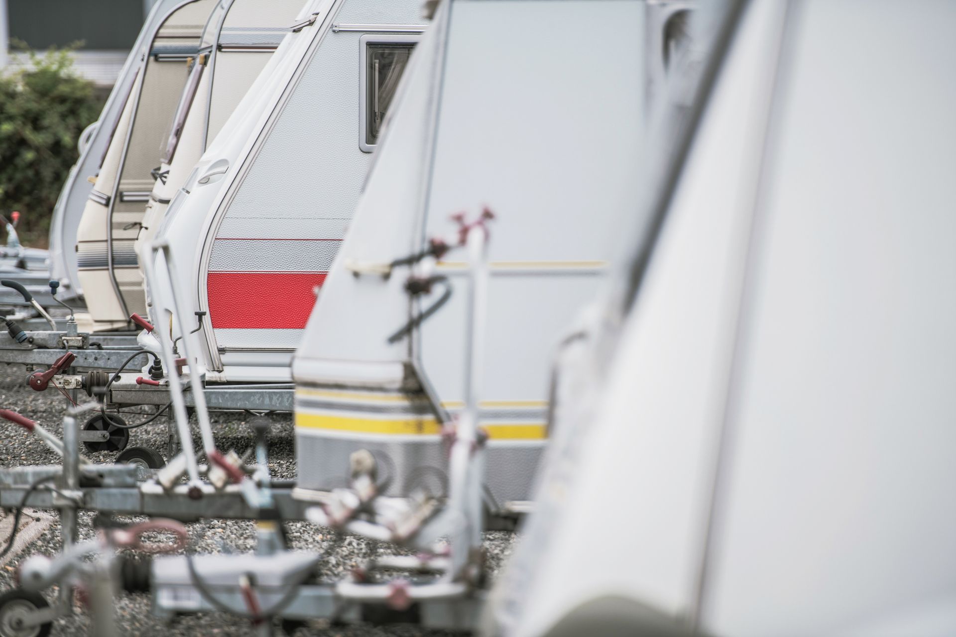 Row of parked camping trailers, white and gray with red and yellow accents.