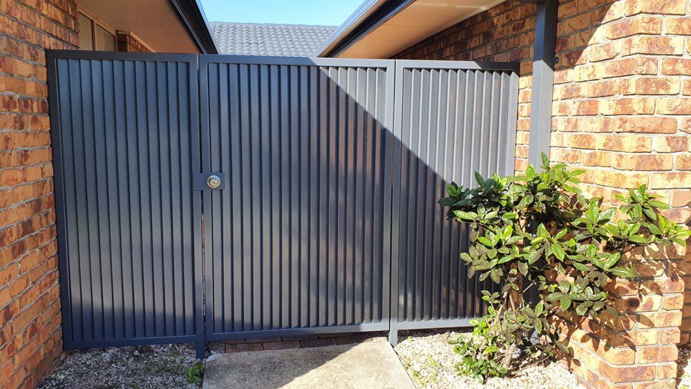 Dark Aluminum Gates On The Bricks Wall — Aluminium Gates in Burleigh Head, QLD