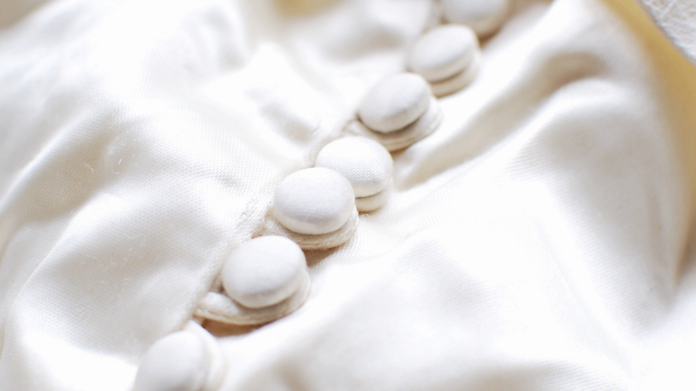 White buttons on a silky, draped fabric.