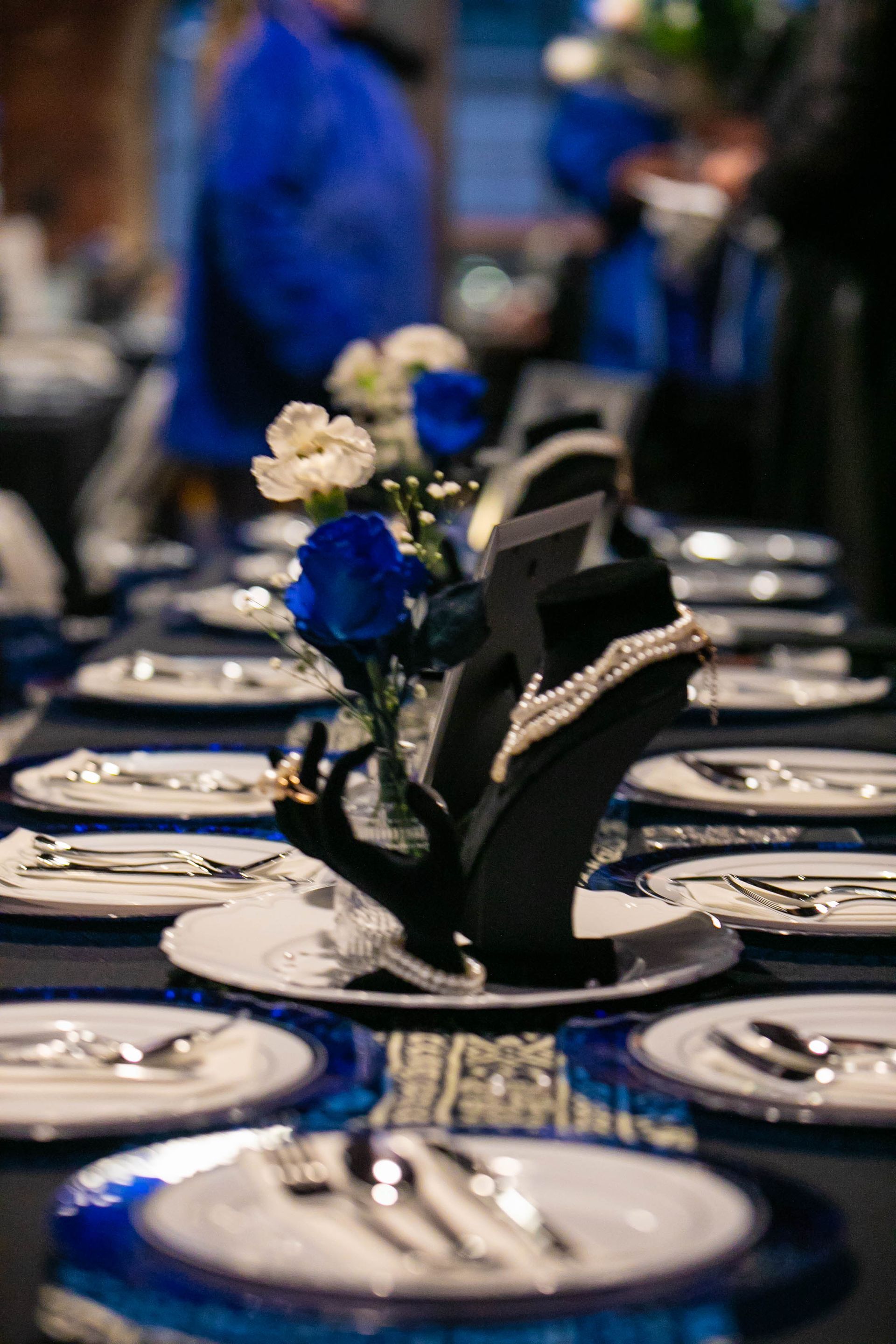 Formal dinner table set with jewelry display and blue and white flowers.