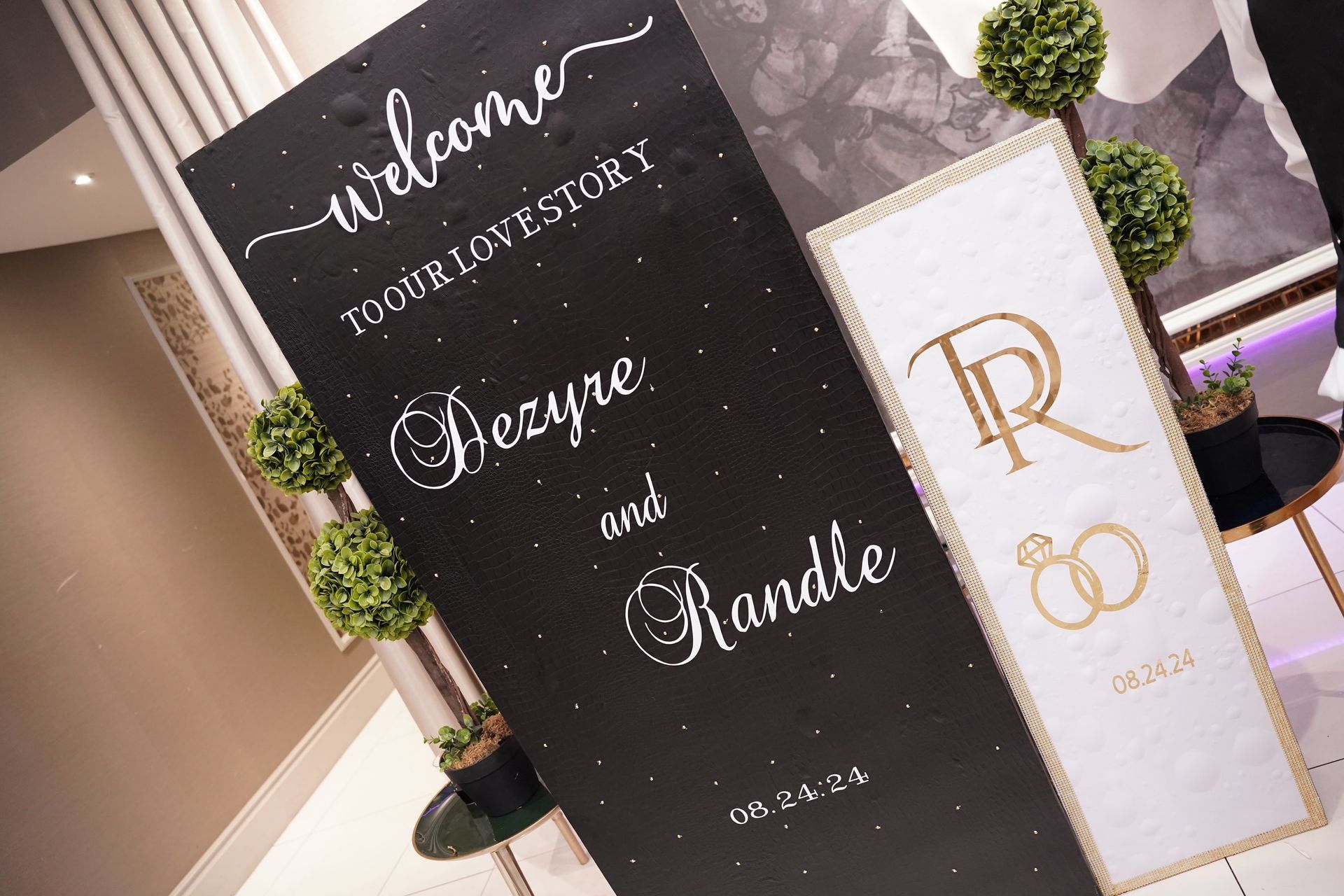 Wedding welcome signs: Black sign with white script, white sign with gold monogram, gold rings.