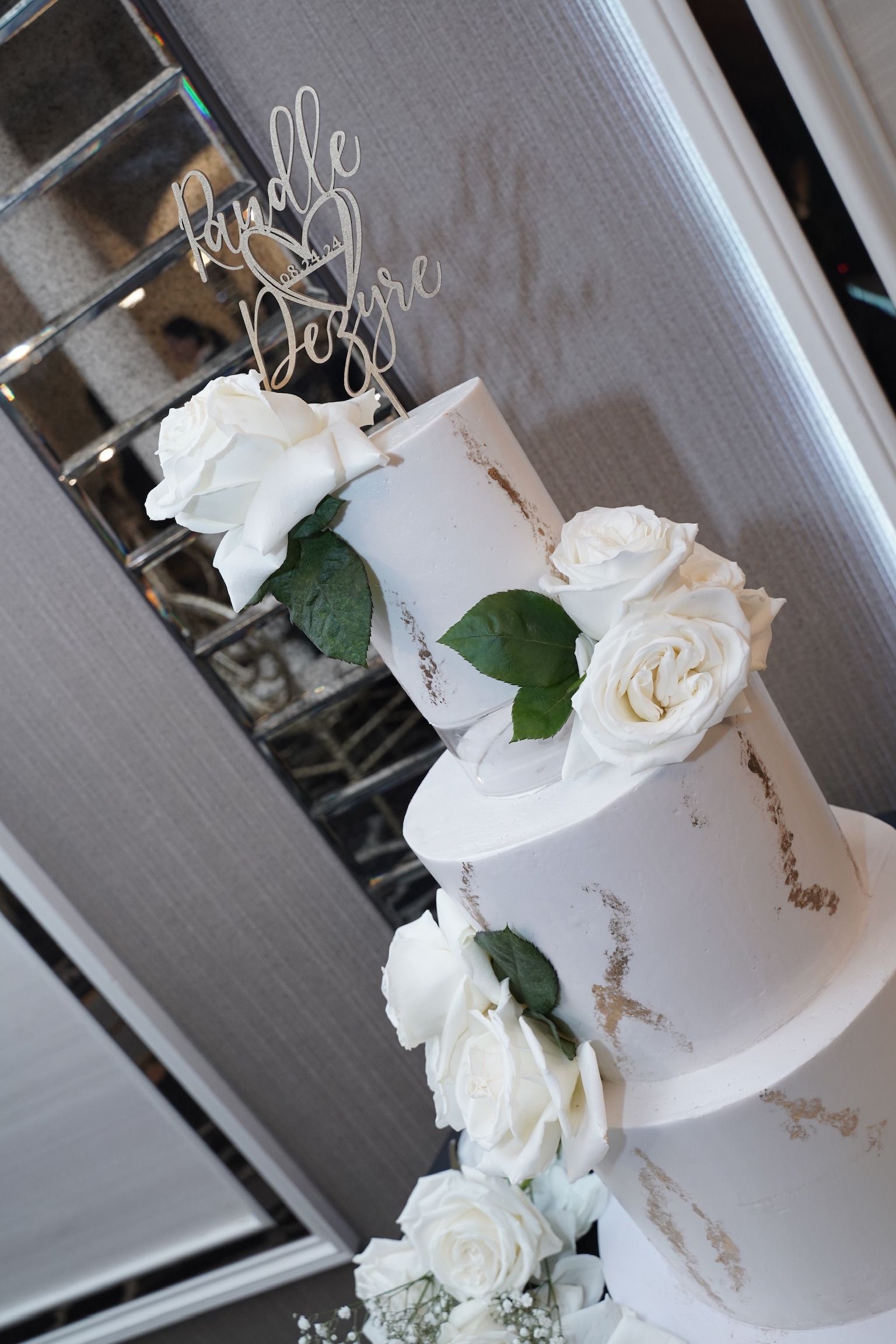 Three-tiered white wedding cake with white roses and a 