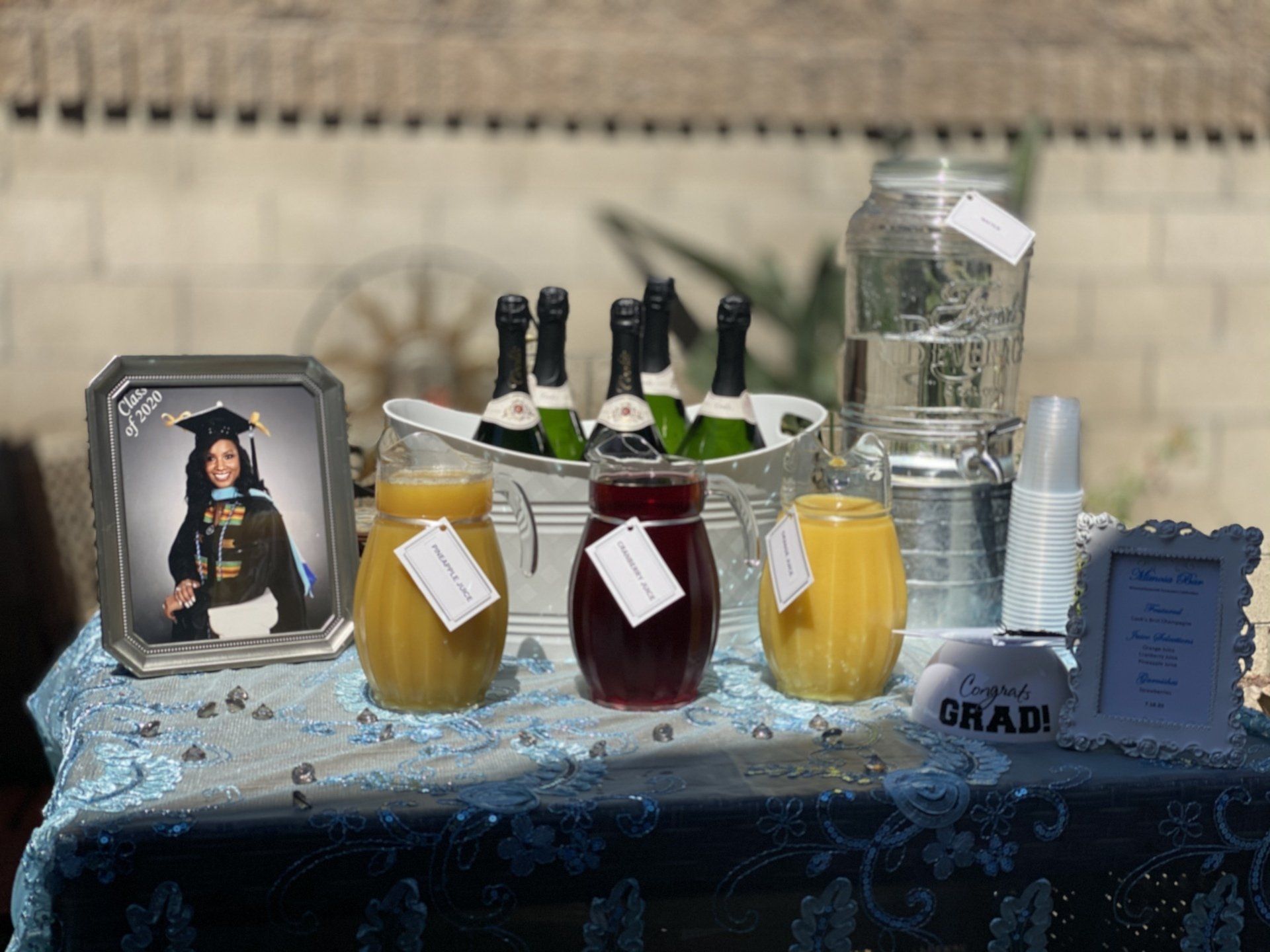 Graduation celebration with drinks, photo, and decorations on a blue table.