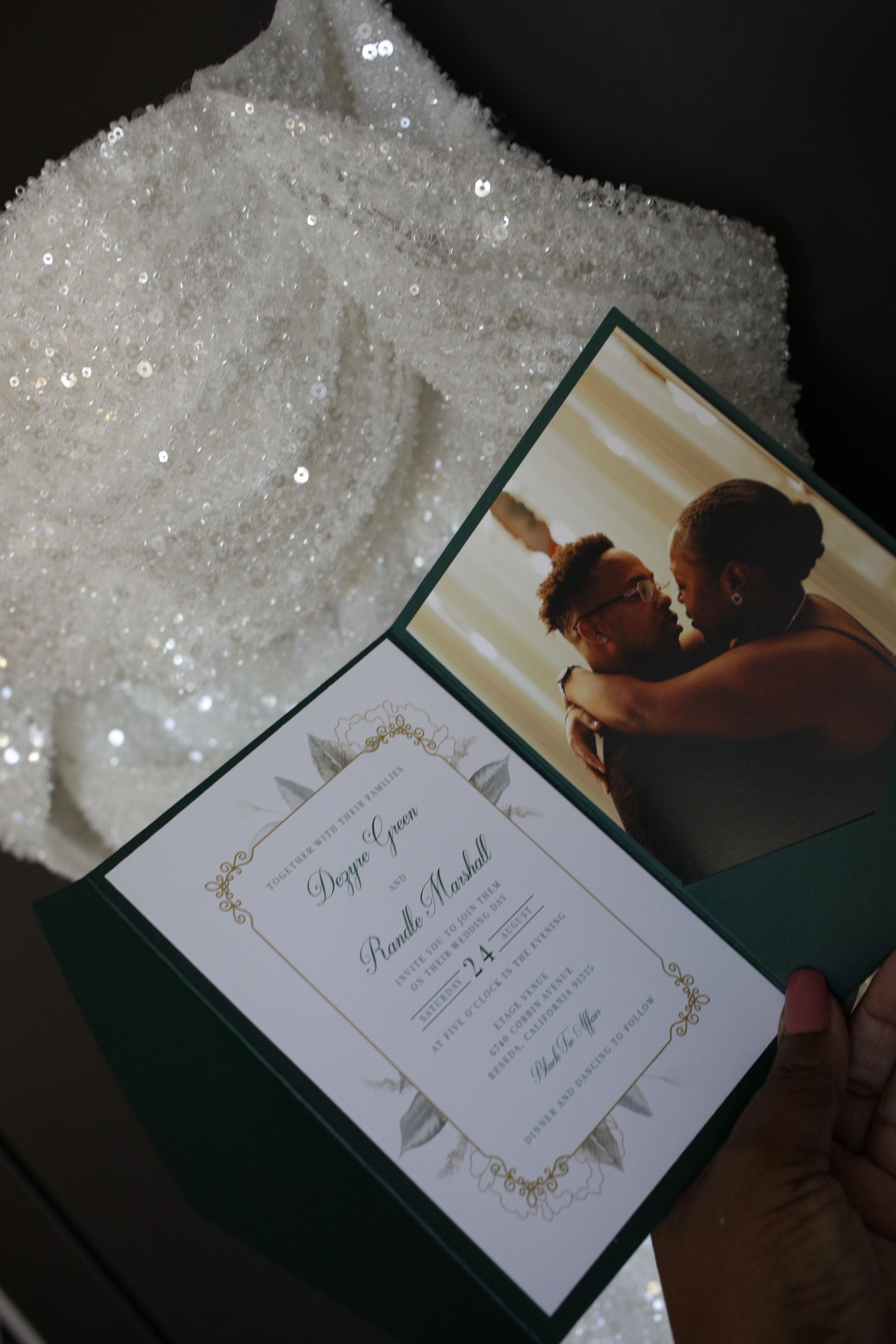 Wedding invitation featuring a photo of a couple; held against a sparkly white dress.