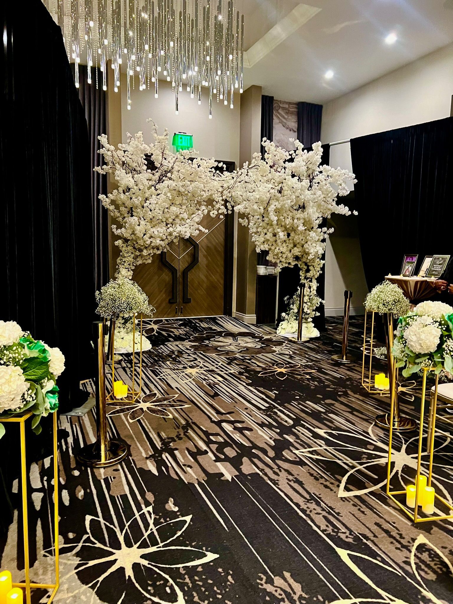 Wedding aisle with floral decorations, gold accents, and a large chandelier.