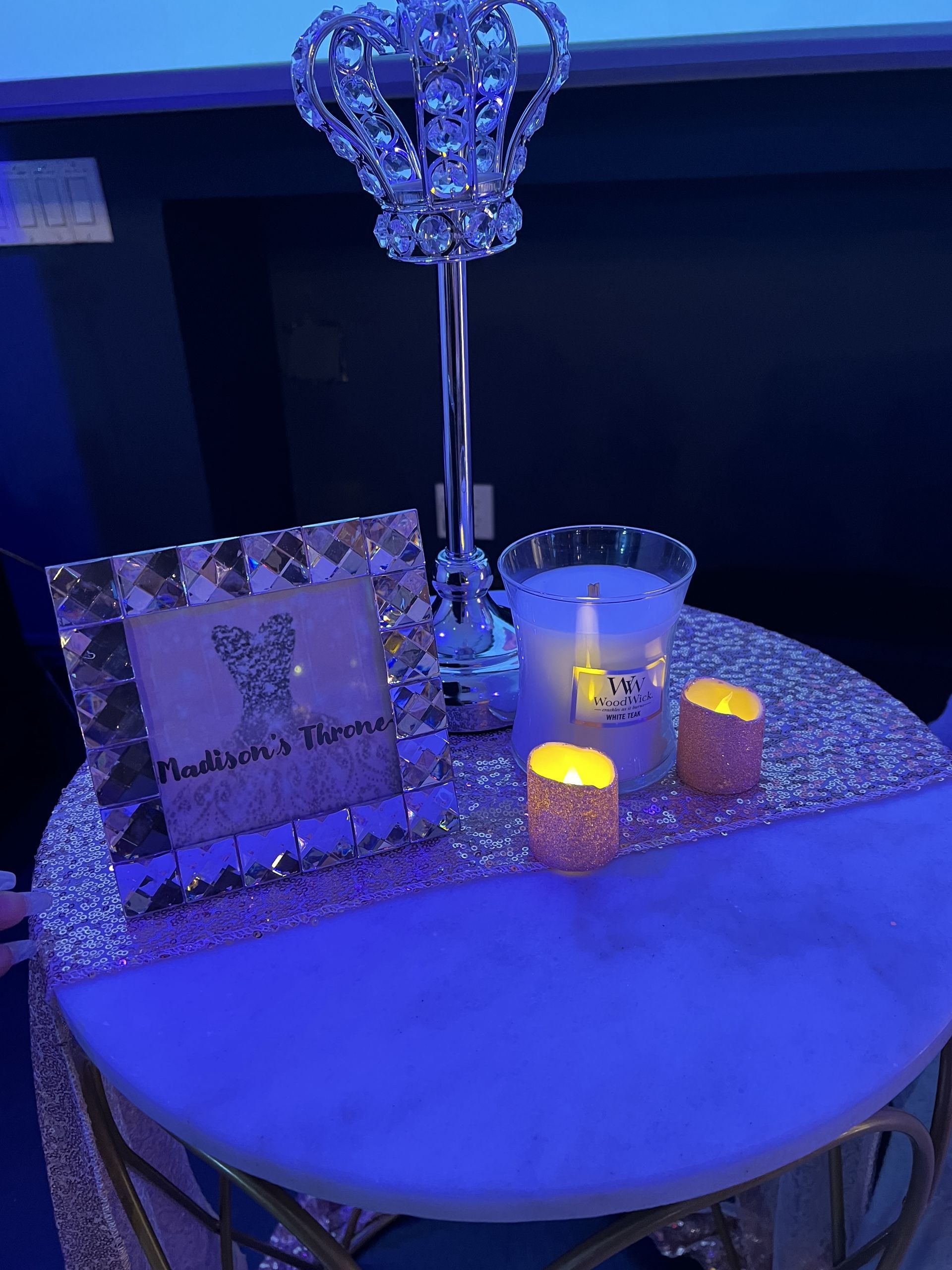 A decorative table with a crown centerpiece, candles, and a framed card with text.
