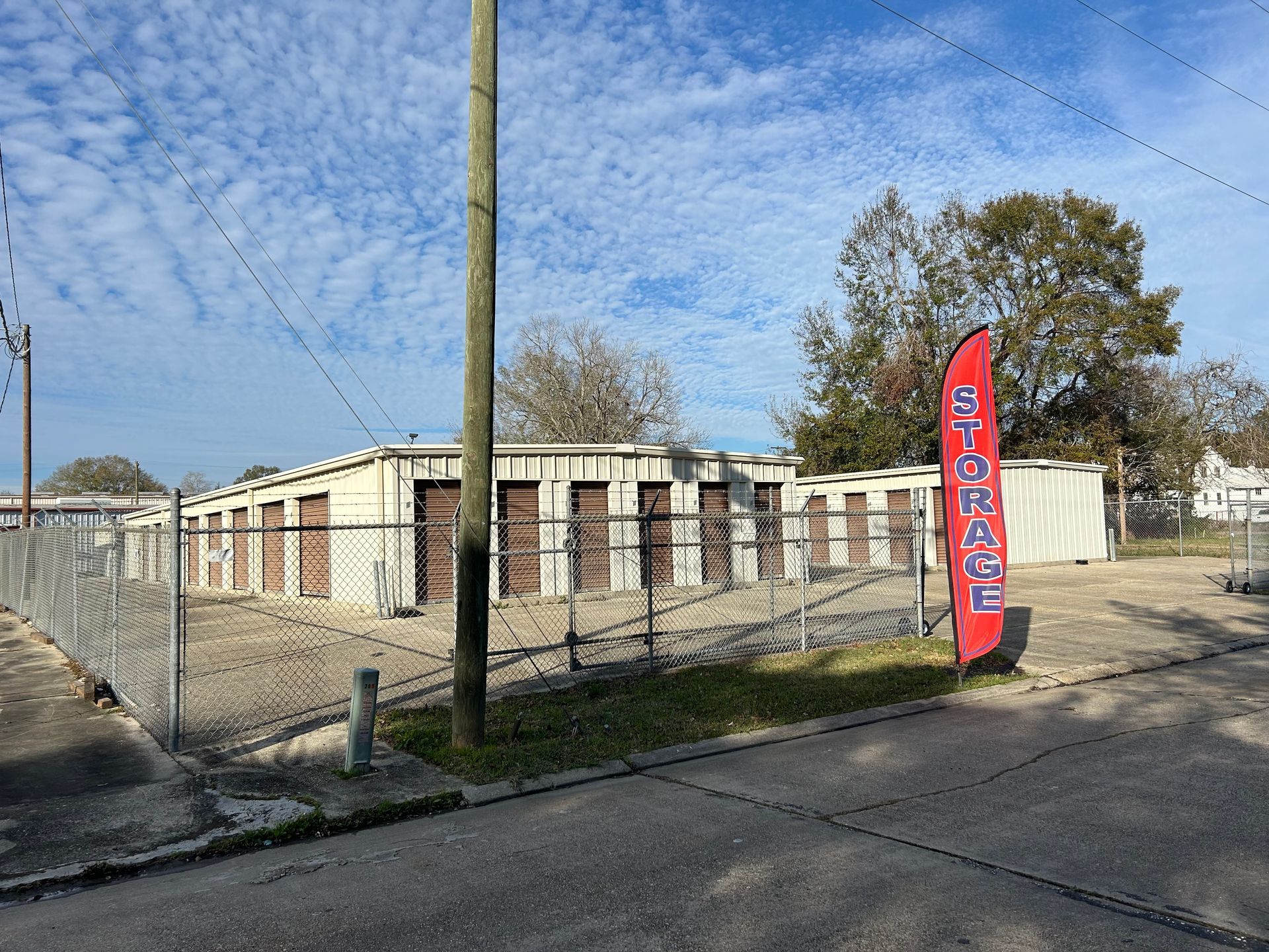 Storage units behind a chain-link fence, with a red and white