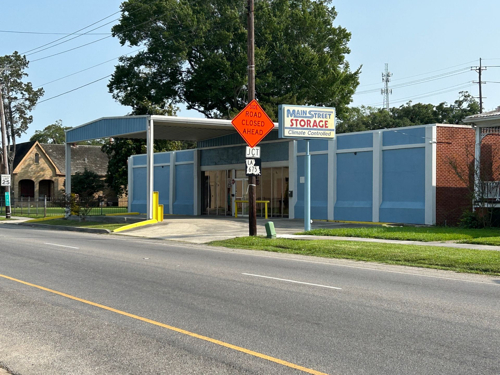 Main Street ITC LLC building, blue exterior, orange work sign, parked car, trees.