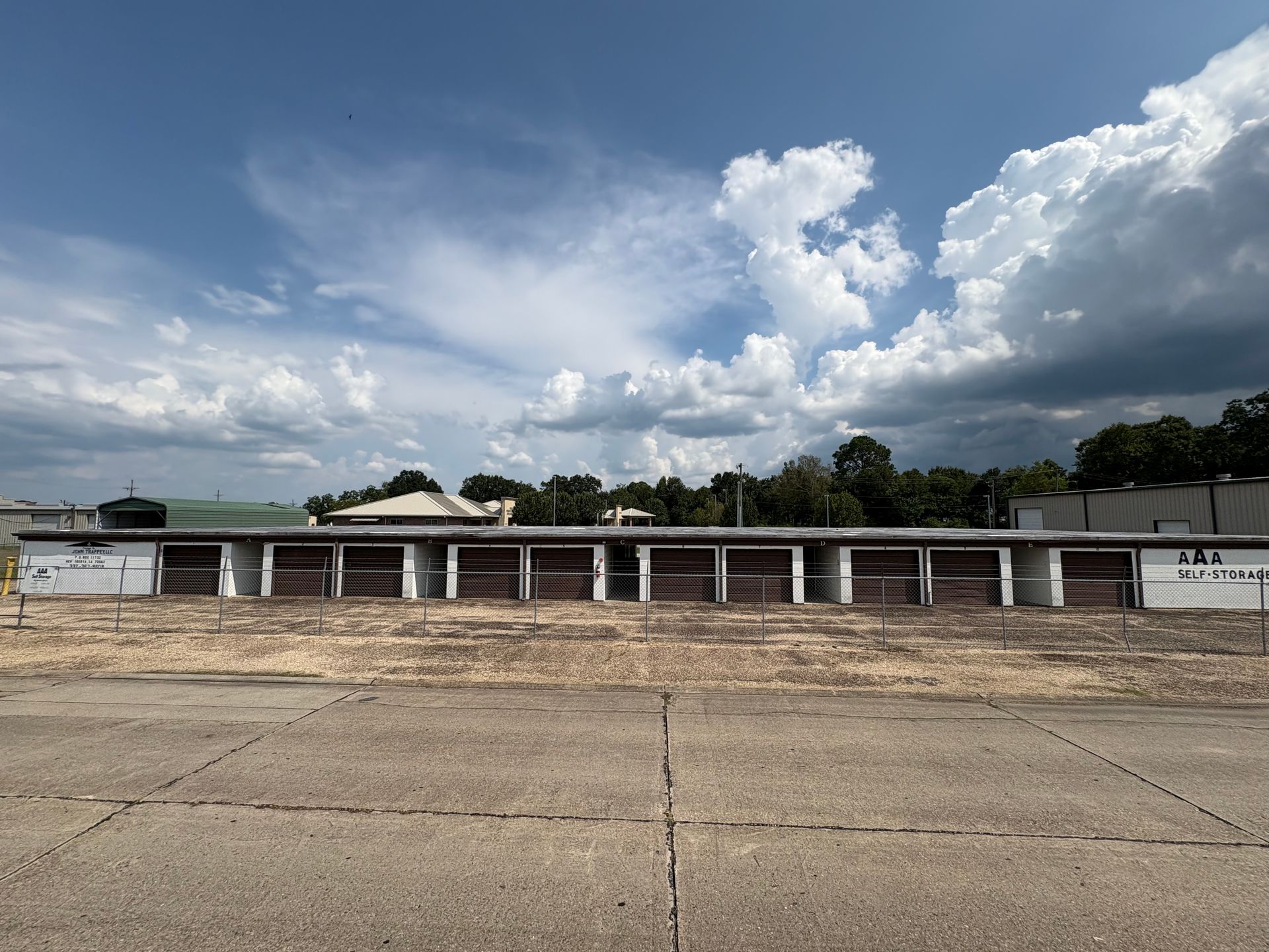 A row of storage units under a cloudy blue sky. Brown doors are closed.