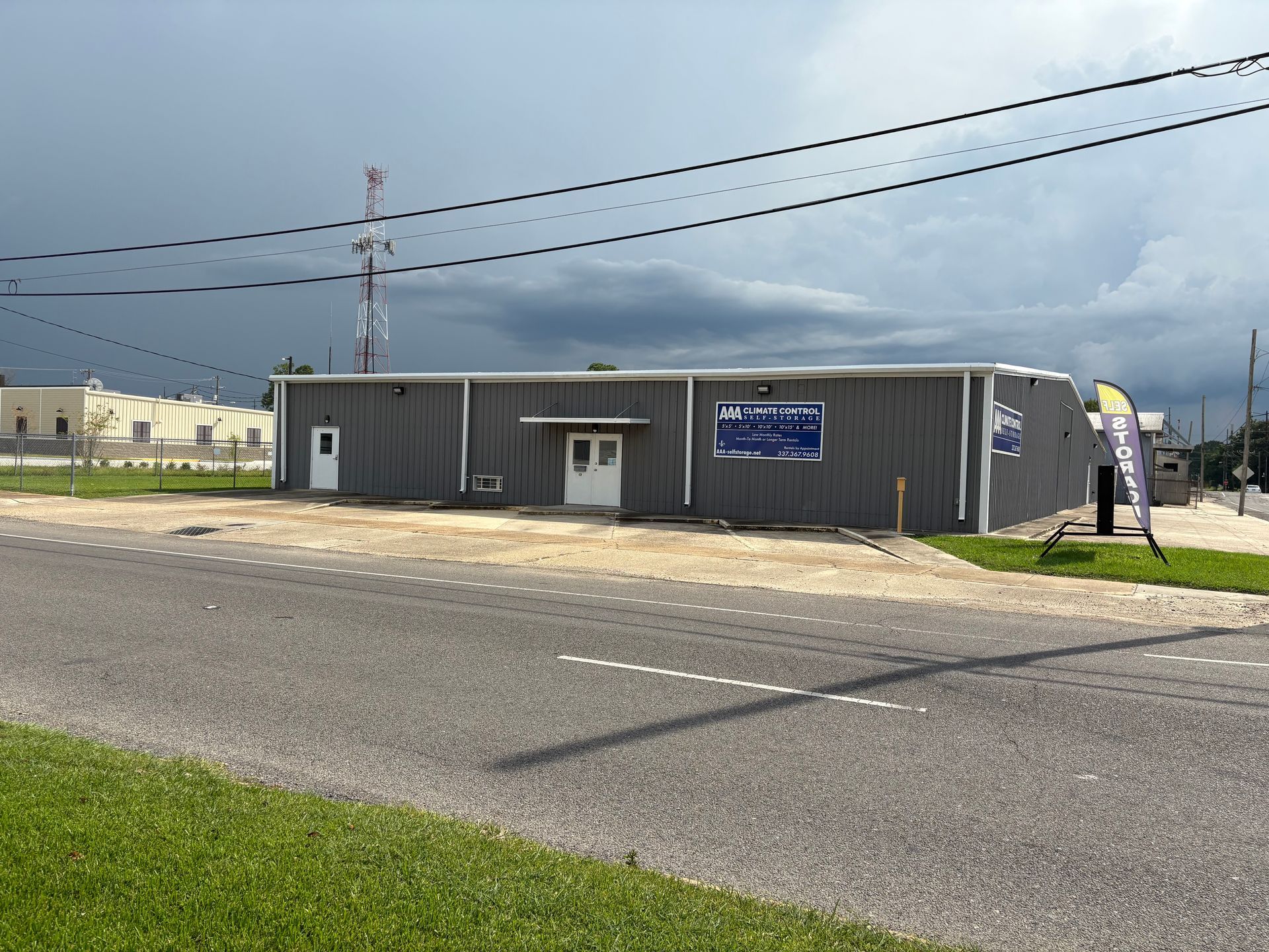 Gray metal building with a sign, under a cloudy sky.