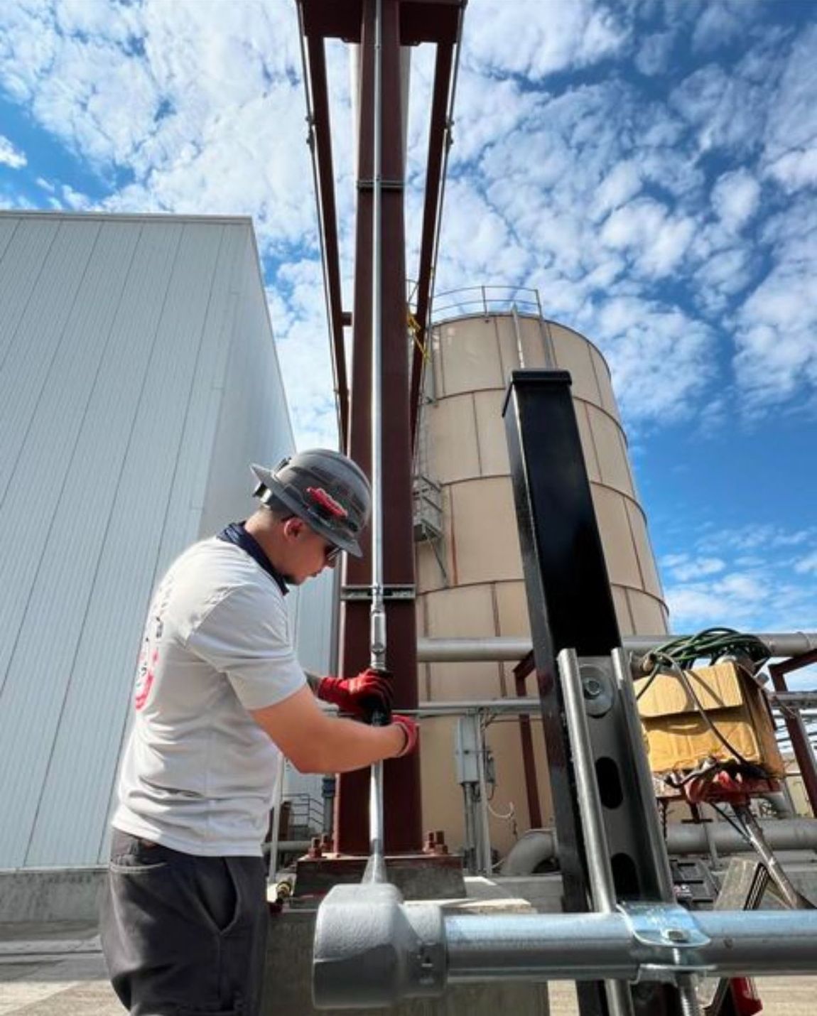 A man is working on a pipe outside of a building.