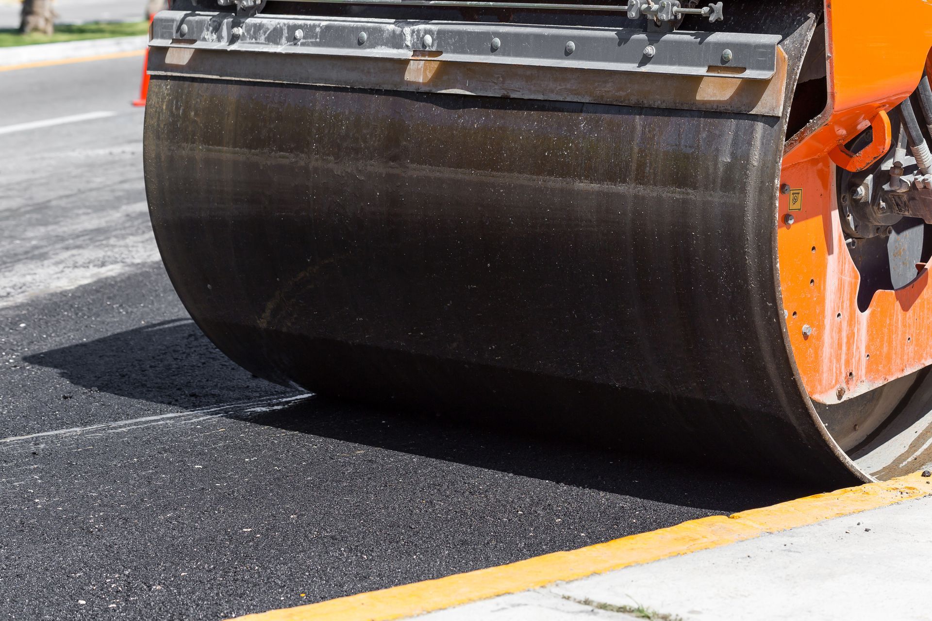 Asphalt roller compacting fresh pavement during road construction for smooth surface area work crews.