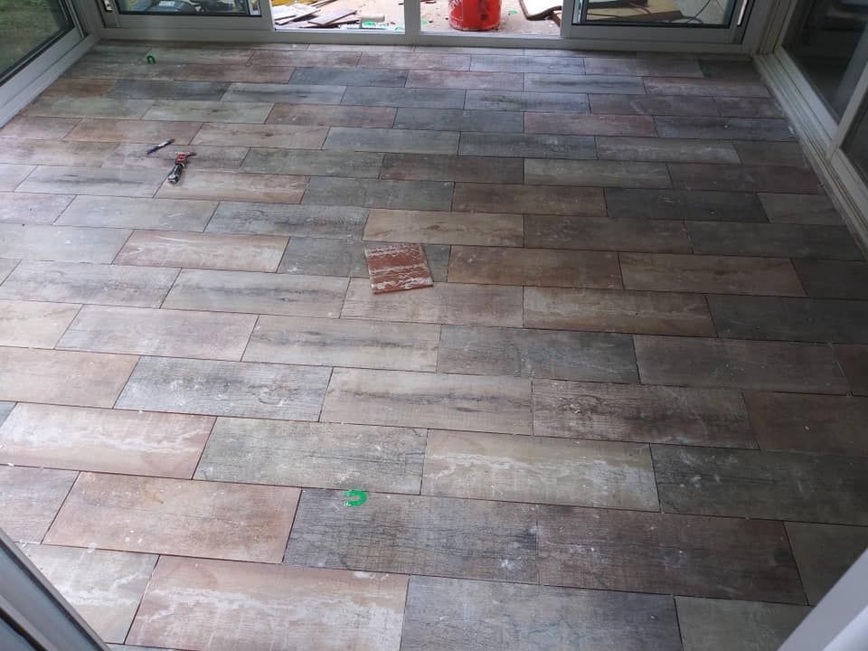 Stone tile flooring in a sunroom with sliding glass doors. Tiles are various shades of brown and gray.