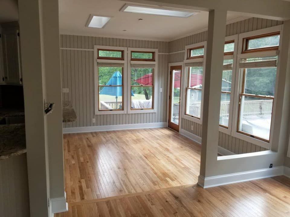Sunroom with wood floors, windows, and neutral walls; a doorway leads outside.