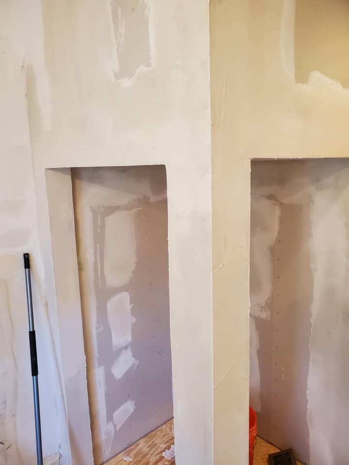 Drywall openings in a light-colored wall, ready for shelving or recessed features.