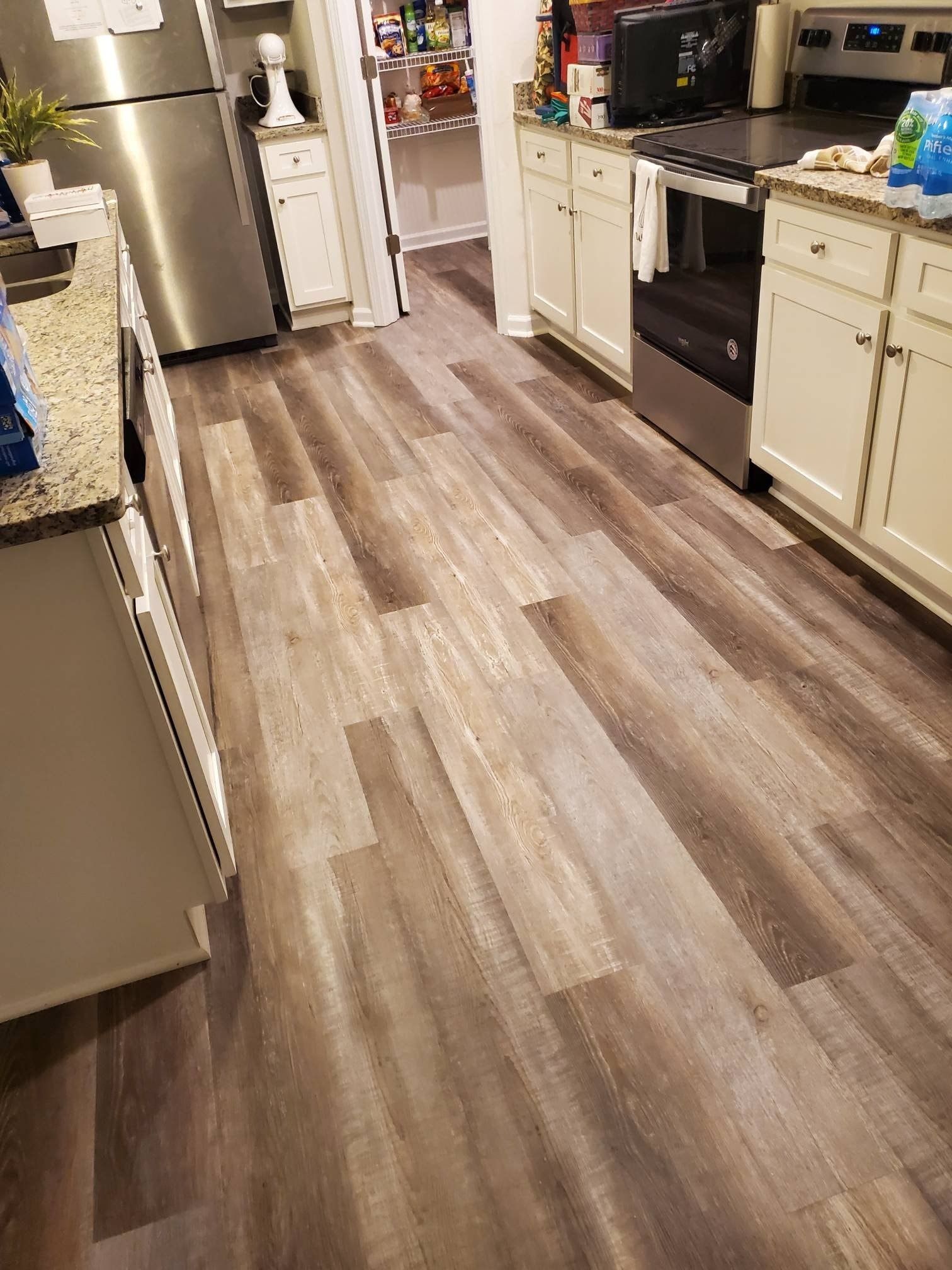 Kitchen with wood-look flooring and white cabinetry. Stainless steel appliances visible.