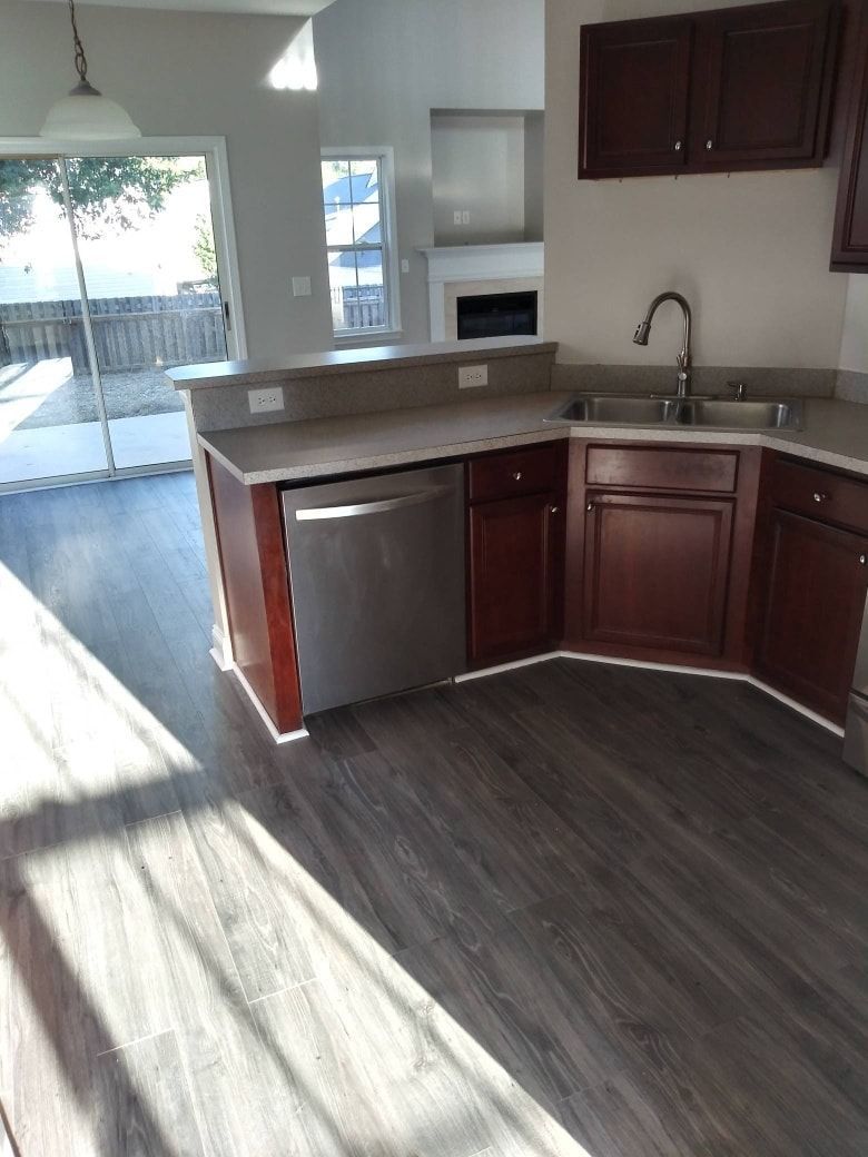 Kitchen with dark cabinets, stainless steel dishwasher, and gray countertop.